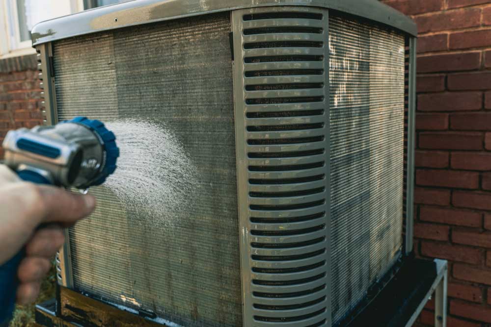 technician inspecting/cleaning an HVAC system