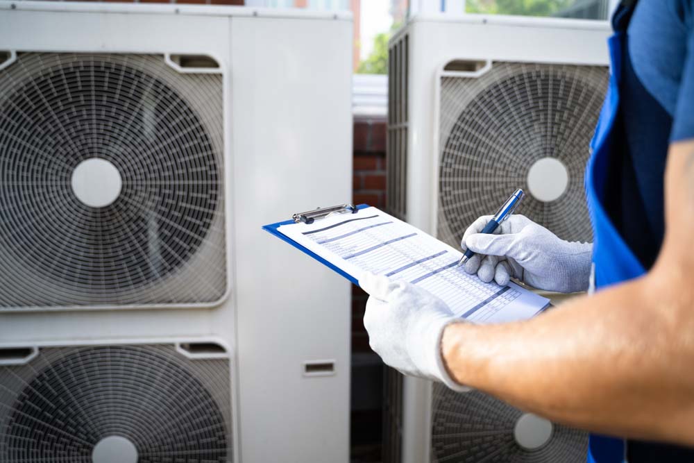 HVAC technician holding a clipboard and inspecting an HVAC system