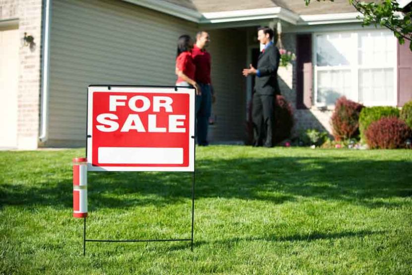 Exterior of an old house with “for sale” signage