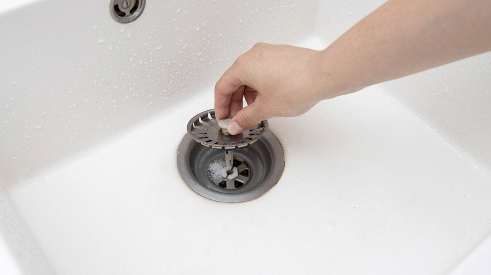 hand placing a strainer on a drain