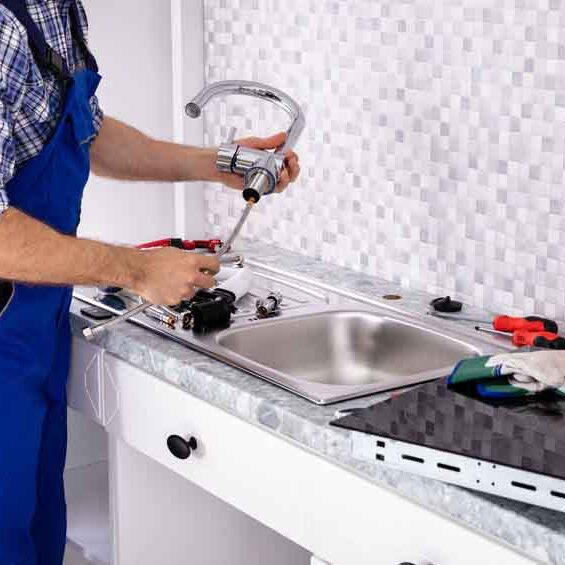 Mid Section Of Male Plumber Assembling The Kitchen Sink Faucet