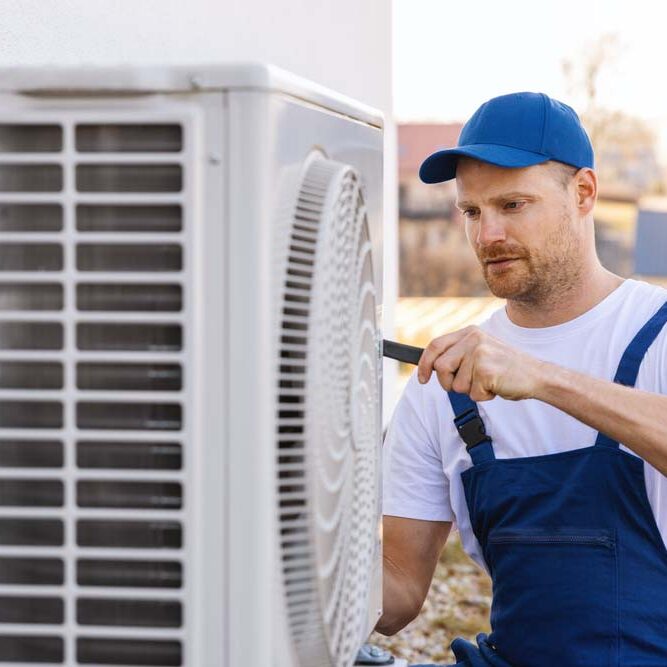 technician working on air conditioning or heat pump outdoor unit. HVAC service, maintenance and repair