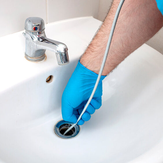 remarkable-benefits-of-drain-snaking Plumbing issues, occupation in sanitation and handyman contractor concept with plumber repairing drain with plumbers snake (steel spiral that twists through pipes to collect dirt) in residential sink